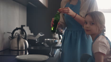 La-Mujer-Y-Su-Pequeña-Hija-Están-Horneando-Panqueques-En-La-Cocina.-La-Madre-Está-Echando-Aceite-En-La-Sartén-Y-El-Niño-Está-Ayudando.